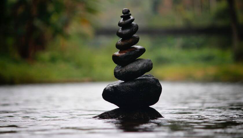 odkrycie-spokoju-wewnetrzna-sila Kamienie ułożone w równowagę na tafli wody – obraz wewnętrznego spokoju, harmonii i siły, którą można w sobie odnaleźć